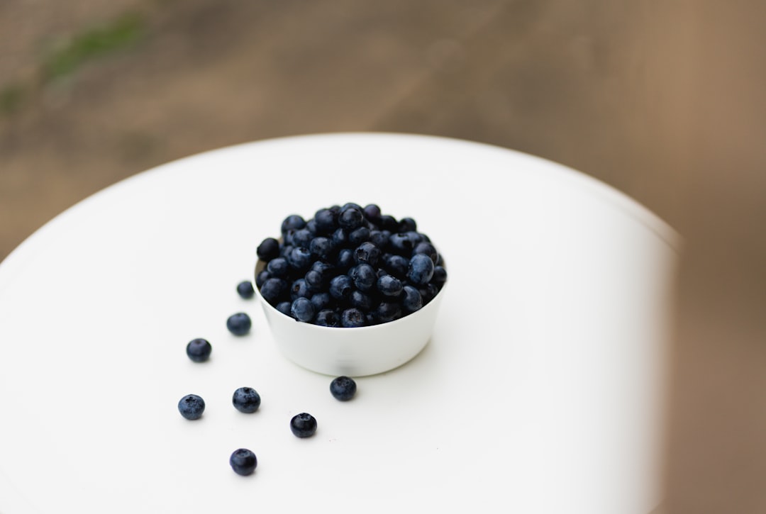 a-white-bowl-filled-with-blueberries-on-top-of-a-white-table-ub-cq5vjarc